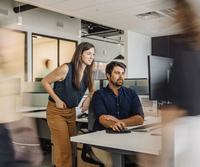 Two Merus employees collaborate at a computer in the office.