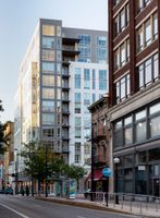 High-rise apartment with white and gray facade in background, and historic buildings in foreground.