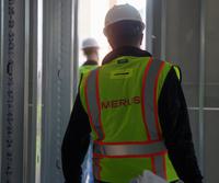 Merus team member in personal protection equipment walking onsite in high-vis vest and hard hat