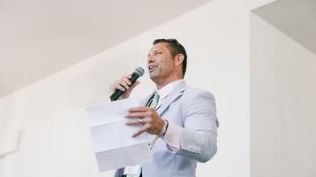 Someone standing on top of a table at an annual event giving a speech