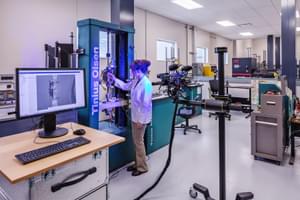 Technician operating testing equipment in a lab with computers and precision instruments