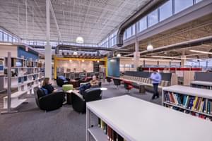 Open office space with bookshelves, seating areas, and large windows circling the top of the room