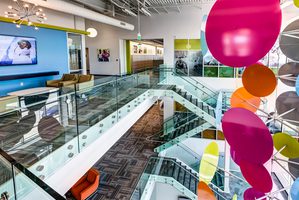 Colorful office interior with glass railings, modern artwork, and a multi-level staircase design