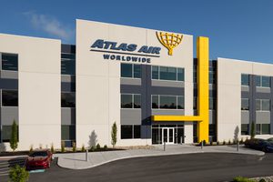 Office building with white facade, yellow accents, and a central glass entrance. Atlas Air Worldwide logo featured on building.