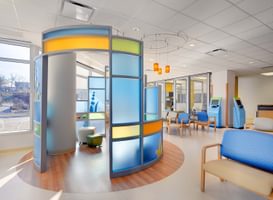 Bright pediatric waiting area with colorful partitions, modern seating, and natural light.