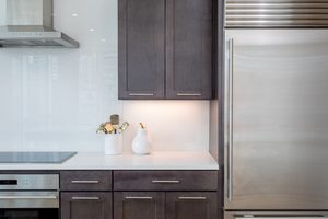 Modern kitchen with dark cabinets, stainless steel appliances, and white backsplash.