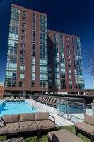 High-rise apartment building with red facade, outdoor pool, and lounge seating.