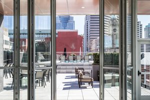 Rooftop terrace with outdoor seating, city skyline views, and glass doors opening to the space.
