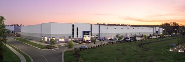 industrial building with white facade and landscaped surroundings at sunset.