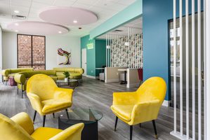 Bright and colorful lounge area featuring yellow chairs, modern decor, and natural light.