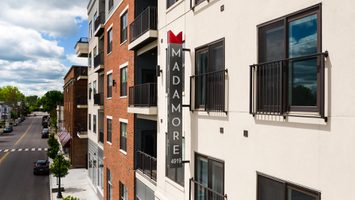Madamore apartment sign on a modern residential building facade, featuring balconies.