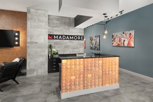 Madamore apartment lobby featuring a modern reception desk and artistic decor.