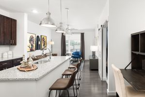 Modern kitchen and living area featuring granite countertops, bar seating, and stylish decor.