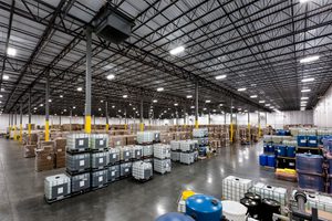 Warehouse interior with pallets, industrial storage containers, and high metal ceilings.