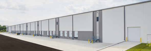 Large warehouse exterior with multiple loading docks, white walls and gray accents.