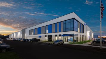 White industrial building with gray and blue accents and a glass facade. The PepsiCo logo is on the side.