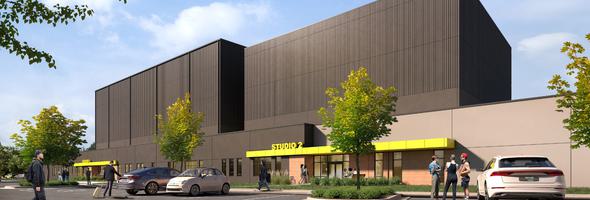 Rendering of a studio building with a sleek dark facade, yellow accents, parking lot, and green landscaping.