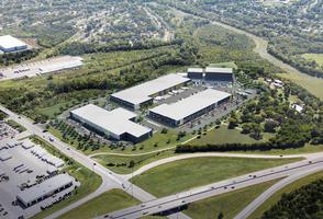 Aerial view of a modern industrial park with multiple large warehouses, parking lots, and green spaces.