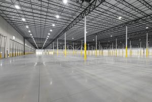 Spacious interior of a warehouse with polished floors, yellow pillars, and high industrial ceilings.