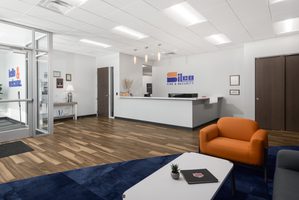 Lobby with wood floors, orange chair, blue rug, and white reception desk, with Silco Fire & Security logo behind on wall.
