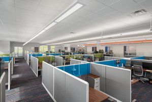 Open office space with gray cubicles, blue and green accents, and a clean, bright interior design.