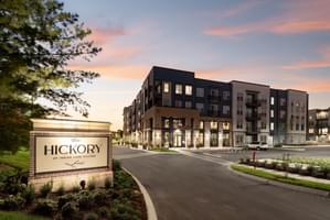 Apartment complex with illuminated The Hickory at Indian Lake Village sign at sunset